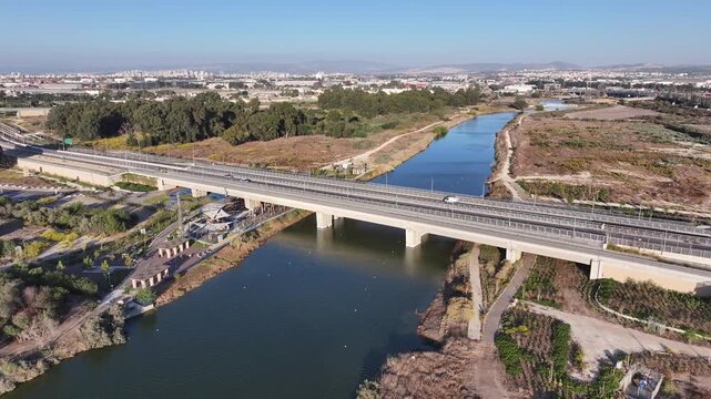 Aerial drone view of traffic on the bridge over the Kishon River with Haifa Bay industrial zone and refineries in the background