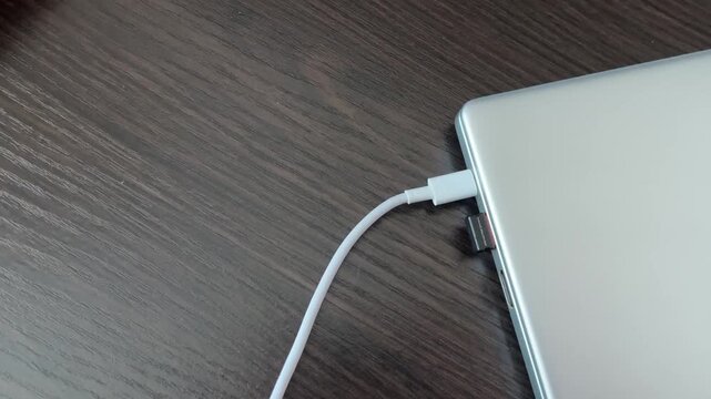 Laptop receives charge through tidy cable connection. Final shot displays cable seamlessly inserted into laptop port. Scene concludes with neatly connected cable supplying power to laptop