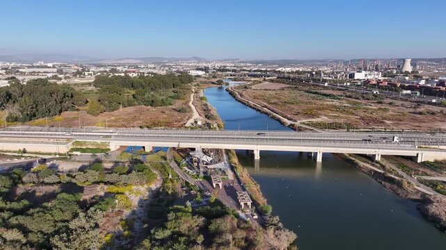 Aerial drone view of traffic on the bridge over the Kishon River with Haifa Bay industrial zone and refineries in the background