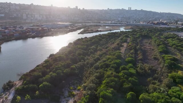 Aerial view of Kishon River park and harbor with beautiful sun flare against Haifa city and Mount Carmel landscape
