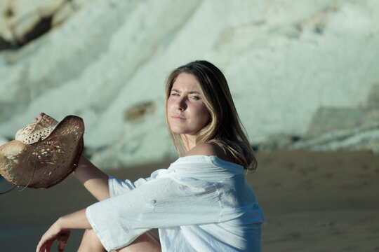 Woman holding straw hat relaxing on beach