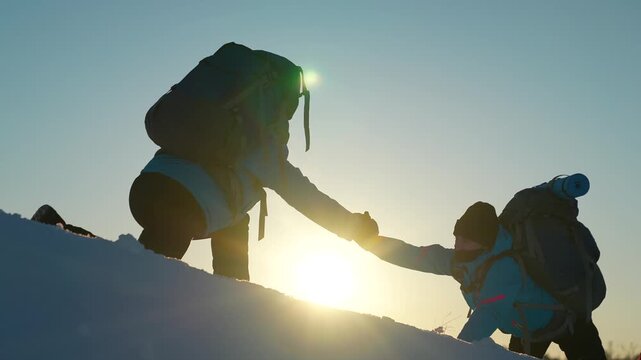 Teamwork in travel. Backpackers climb mountain together. Business teamwork. Reach your goal. Climbers, holding hands, climb to top hill. Silhouettes. Business team victory. Free people strive victory