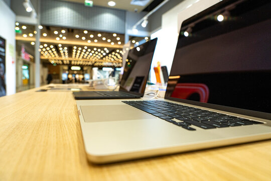 High-Tech Laptops Displayed in Modern Retail Environment Featuring Bright Lights and a Stylish Wooden Counter for Contemporary Shopping Experience
