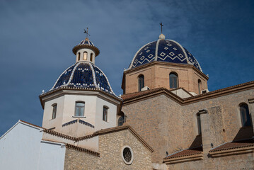 Fototapeta premium Blue tiled domes of Nuestra Señora del Consuelo church in Altea, Alicante, Spain, iconic Mediterranean architecture with ceramic tile patterns under dramatic sky.