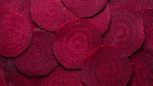 Organic red beetroot slices background. Fresh organic beetroot texture, close up, top view. Heap fresh colorful beet, rotates