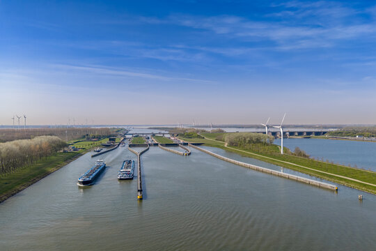 Aerial view of the Volkerak Locks with cargo barges in the approach canal, A29 bridge and wind turbines, Dutch Delta Works, Netherlands