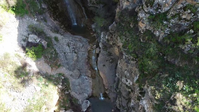 Top down view of small waterfall cascading into rocky pond in deep mountain gorge, pristine nature, Tian Shan mountains, Kazakhstan. High quality 4k footage