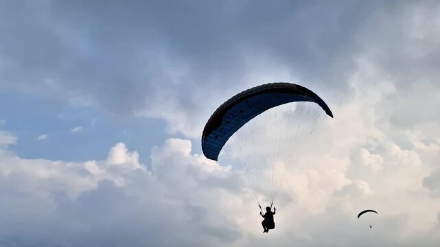 Malang, Indonesia - 3 May, 2026: Paraglider Flying High in Cloudy Sky Symbolizing Freedom and Adventure Over Mountain Valley