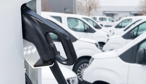 Electric vehicles charging station on a background of a row of vans. Green transportation concept