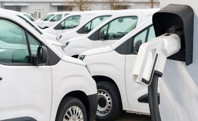 Electric vehicles charging station on a background of a row of vans. Green transportation concept