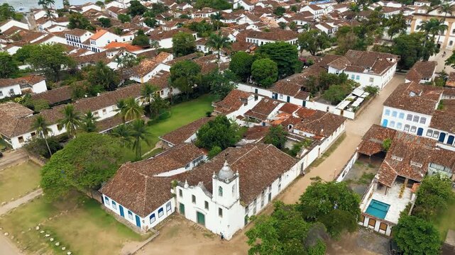Aerial view of Church of Our Lady of Sorrows and First Church with colonial rooftops in historic Paraty, Brazil. Push in diagonal camera movement