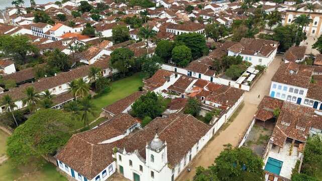 Aerial view of Church of Our Lady of Sorrows, First Church and main square with colonial rooftops in historic Paraty, Brazil. Push in diagonal camera movement
