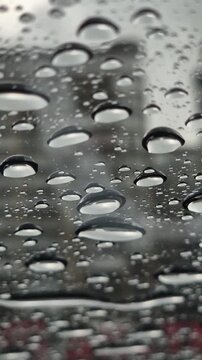 Raindrops dripping onto panoramic glass from above, close-up
