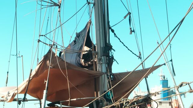 Traditional sailboat mast and rigging in marina against clear sky, capturing nautical adventure, maritime craftsmanship and coastal sailing lifestyle themes.