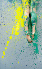 Bare legs covered in green paint resting on splattered surface with vivid yellow pigment creating an abstract artistic composition full of texture movement and creative energy © ullision