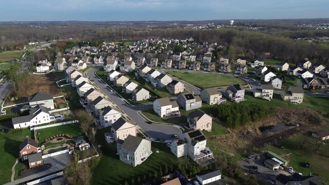 Elevated suburban sweep shows homes along Straw Lily Way near Forge Road with wooded buffers leading toward Gunpowder Falls State Park. Warm shingles, trimmed lawns soft afternoon tones, Maryland