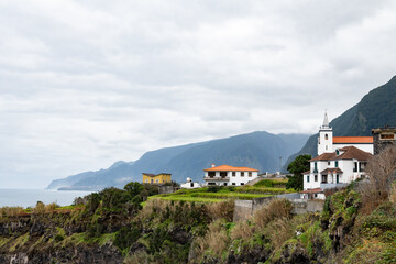 Naklejka premium picturesque coastal village with church overlooking rocky cliffs under cloudy sky
