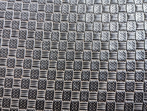 Close-up view of a dark grey textured surface with a basket-weave pattern.