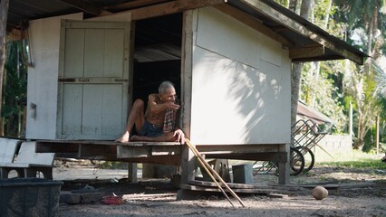 Fototapeta premium Old asian man relaxing at home in rural village, peaceful simple lifestyle