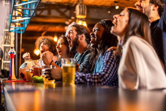 Friends passionately cheering during soccer match in a pub