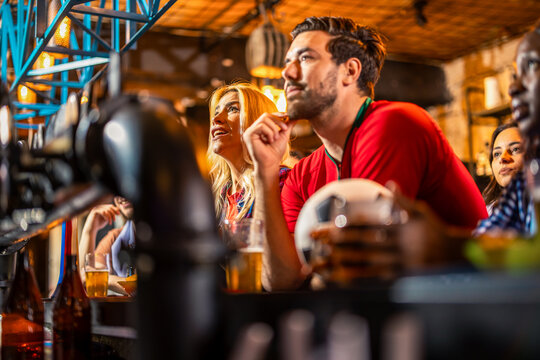 Group of friends watching soccer match with beer on pub counter