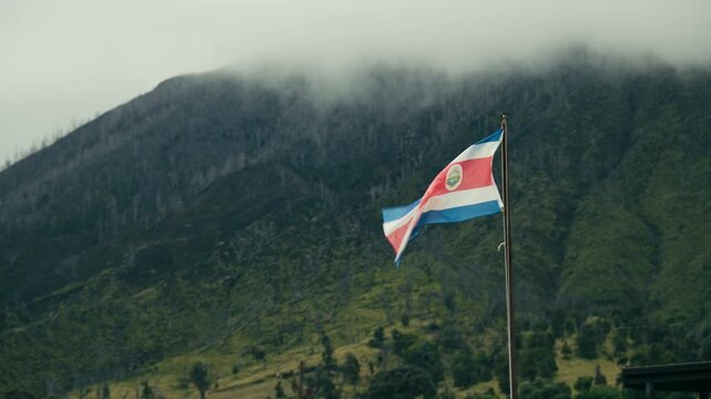 Costa Rican flag flying with the Turrialba volcano shrouded in fog in the background