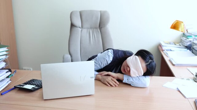 Business woman in a mask blindfolded asleep in the office. Exhausted employee in the workplace