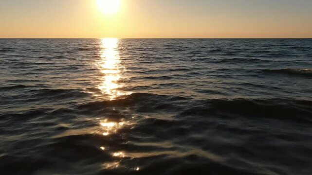 Sunset reflecting on calm ocean waves at golden hour