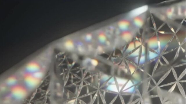 Close-up abstract view of a prism refracting light into a spectrum of colors, creating a geometric pattern on a reflective surface