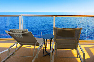 Naklejka premium Two reclining lounge chairs on a private stateroom balcony of a cruise ship cabin overlooking the blue Mediterranean Sea.