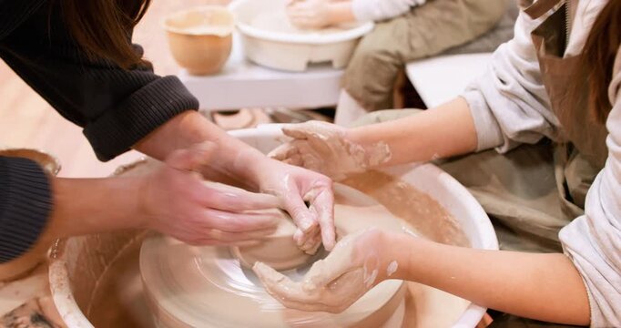 Art education. Creative learning. Unrecognizable woman master hands teaching girls pottery ceramic in class using electric professional wheel.
