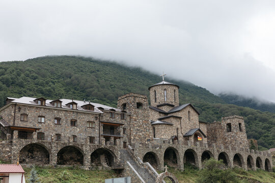 Wide view of Alansky Holy Dormition Monastery, a stone Orthodox complex in the Caucasus Mountains near Fiagdon, North Ossetia&ndash;Alania, Russia, under low clouds