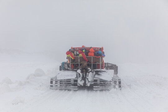 Rear view of a snowcat transporting climbers through a blizzard and low visibility on Mount Elbrus, Kabardino-Balkaria, Russia, winter mountain expedition scene