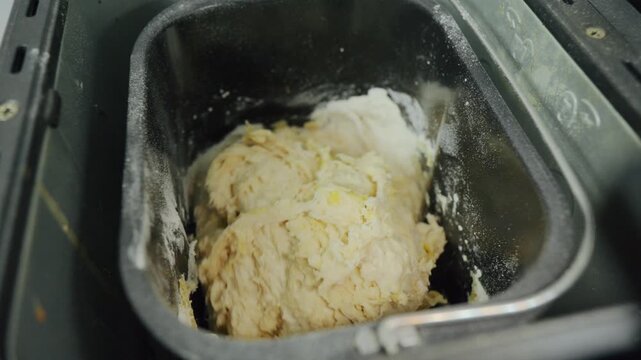 Raw dough being mixed inside a bread machine pan. Shows the elastic texture of the dough