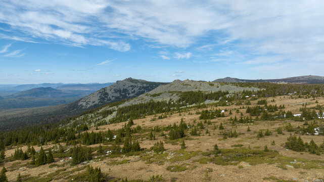 Wide mountain landscape of Bolshoy Iremel near Tyulyuk with rocky ridge, sparse conifer forest and alpine meadow under clear spring sky, Bashkortostan, Russia