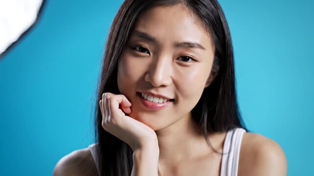 Young Asian woman posing with chin on hand in studio