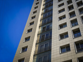Fototapeta premium Modern residential building with dramatic perspective and blue sky, urban architecture background