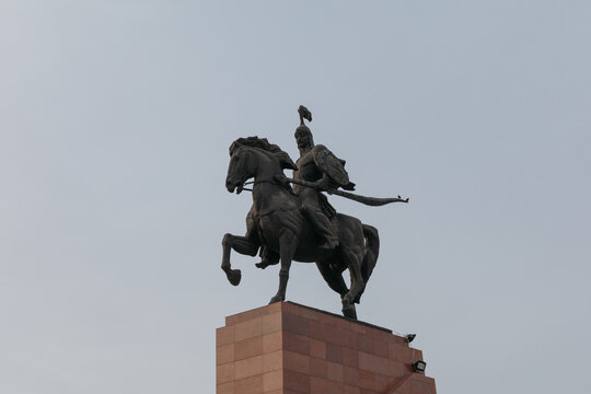 Low-angle view of the Manas equestrian monument atop a stone pedestal at Ala-Too Square in Bishkek, Kyrgyzstan, against a clear evening sky with copy space