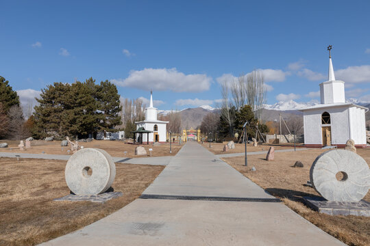 Wide walkway through the Ruh Ordo cultural complex with small chapels, stone monuments and winter landscape, Cholpon-Ata, Issyk-Kul Region, Kyrgyzstan