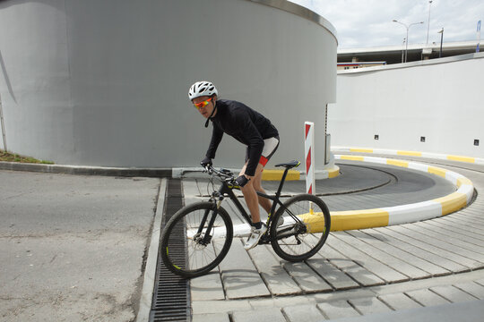 Professional cyclist riding road bike near modern industrial buildings. Training, endurance and active lifestyle concept.