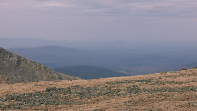 Wide panoramic view from Konzhakovsky Kamen across rocky mountain tundra and alpine meadow toward layered misty ridges of the Northern Urals, Sverdlovsk Oblast, Russia