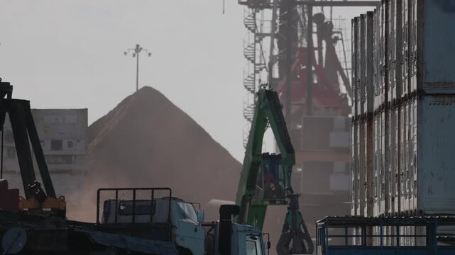Cargo loading takes place at a busy port with cranes and trucks working during the day