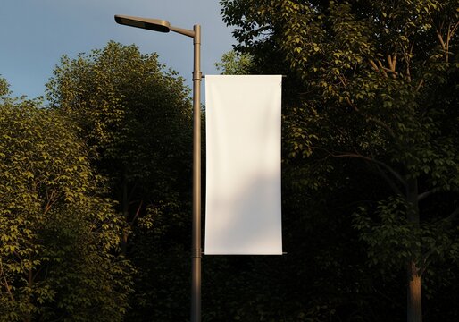 Blank white banner hangs from a streetlight post amidst lush green trees