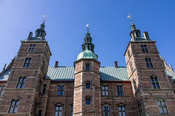 Fototapeta premium Majestic upward view of Rosenborg Castle in Copenhagen, Denmark, showcasing its stunning architecture against a clear blue sky.