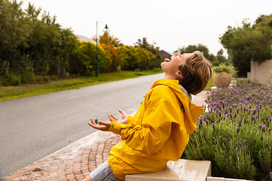 young boy wearing yellow raincoat enjoying the rain