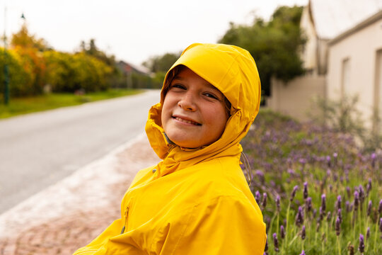 young boy wearing yellow raincoat enjoying the rain