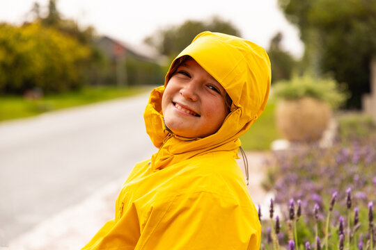 young boy wearing yellow raincoat enjoying the rain