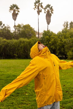 young boy wearing yellow raincoat enjoying the rain