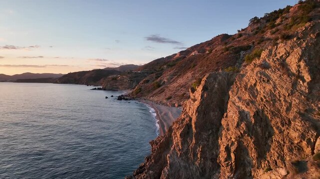 Cinematic Drone Flight Along Sunset-Glowing Red Cliffs Revealing Secluded Beach Near Nerja, Andalusia, Spain