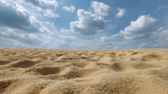 Rippled sand foreground contrasted against a vast dynamic blue sky filled with scattered white clouds